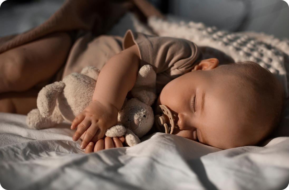A sleeping baby holding a stuffed animal, cozy and screen-free at bedtime